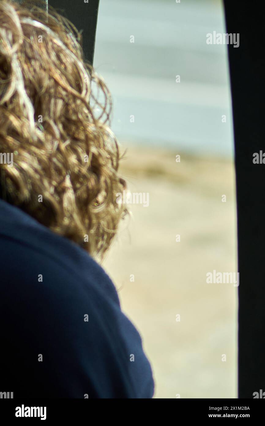 Una persona viene vista da dietro ad osservare una spiaggia calma e serena, catturando un momento di riflessione e connessione con la natura, perfetto per temi di tranq Foto Stock