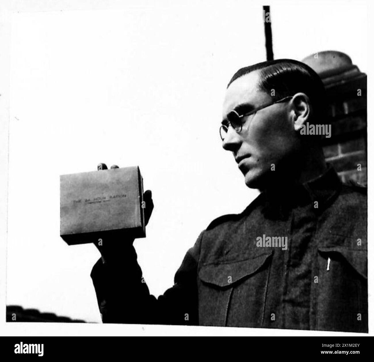 Un soldato dell'esercito britannico tiene un pacchetto di 24 ore per la razione, dimostrando forniture alimentari militari e provviste standard sul campo. Foto Stock