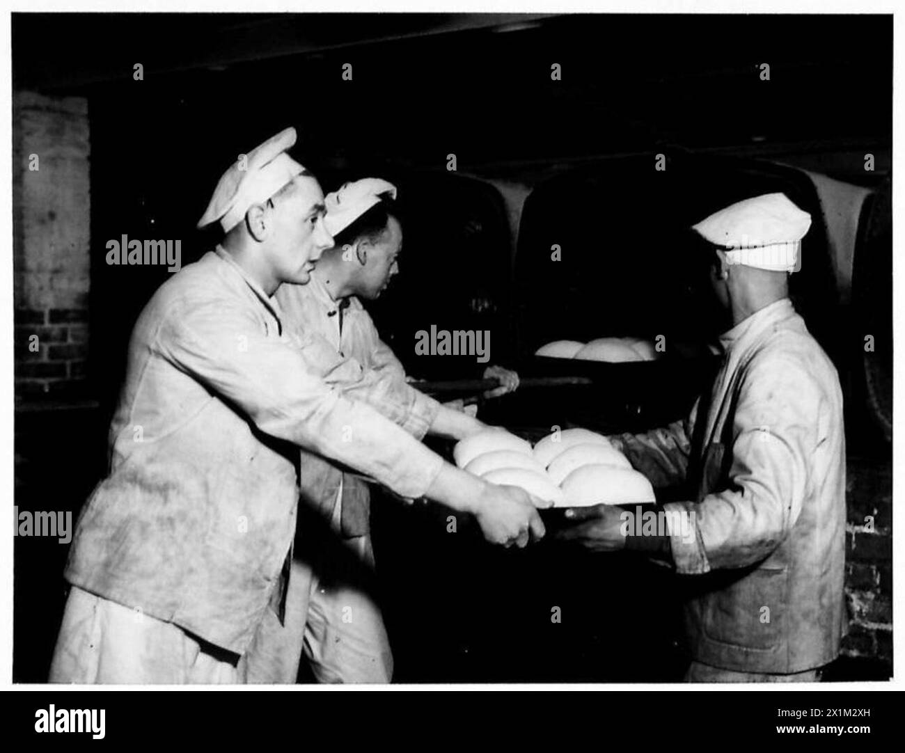 Il personale dell'esercito posiziona i pani nei forni come parte del processo di cottura del pane per le razioni dell'esercito britannico. Foto Stock