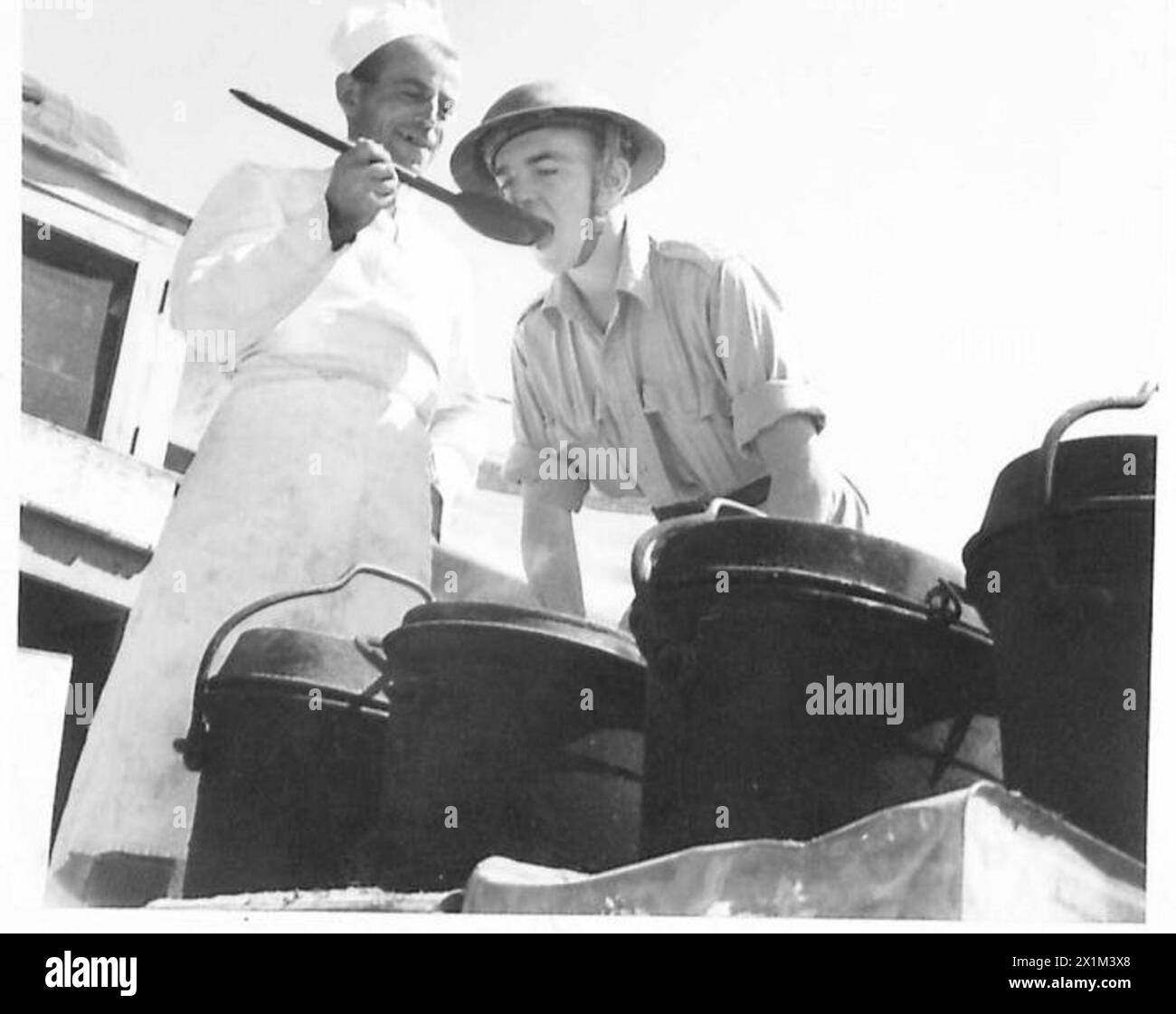 VITA IN Un PICCOLO CAMPO NEL DESERTO - il cuoco prova un nuovo piatto sul suo assistente, British Army Foto Stock
