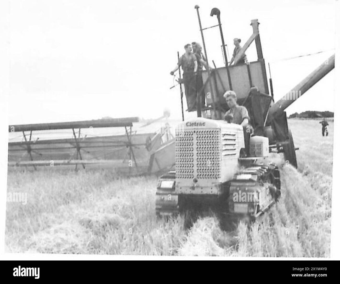 I soldati dell'esercito britannico gestiscono una mietitrice combinata durante il raccolto agricolo, sostenendo la produzione alimentare. Foto Stock