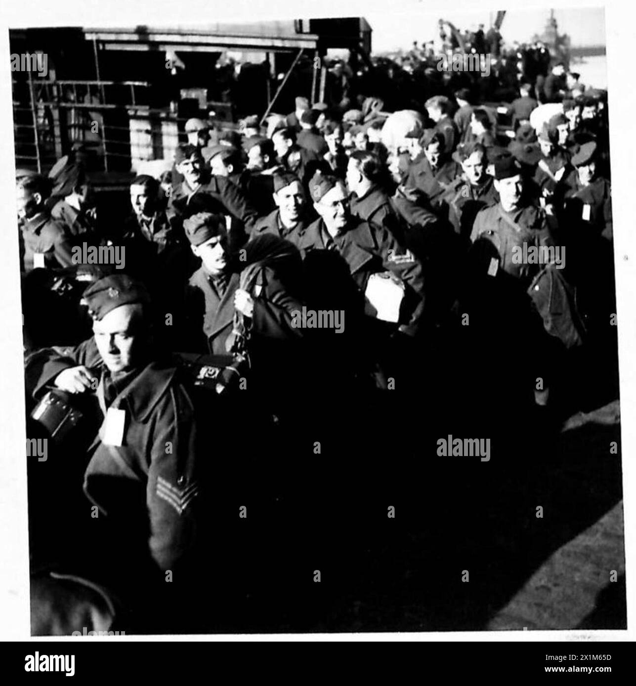 Soldati britannici, australiani e canadesi sbarcano da un tender durante il rimpatrio dei prigionieri in una banchina. Foto Stock