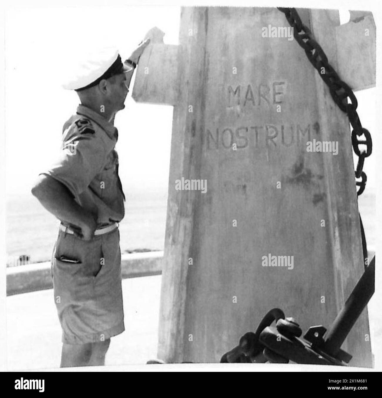 Il tenente J.D. Maitland, RCNVR, osserva l'iscrizione "Mare Nostrum" su un'asta di bandiera nel porto di Augusta dopo che la città è sotto il controllo dell'esercito britannico. Foto Stock