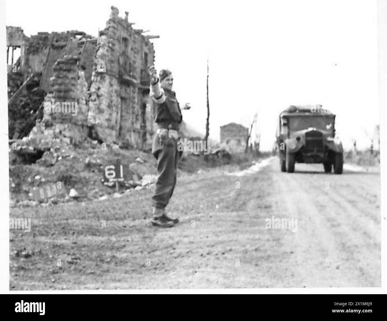 Il caporale A. Thomas della N.E. Provost Company dirige il traffico in un incrocio danneggiato dalla battaglia sulla Route 6, a nord di San Vittore, sotto osservazione nemica, mentre le provviste si spostano a Cassino. Foto Stock
