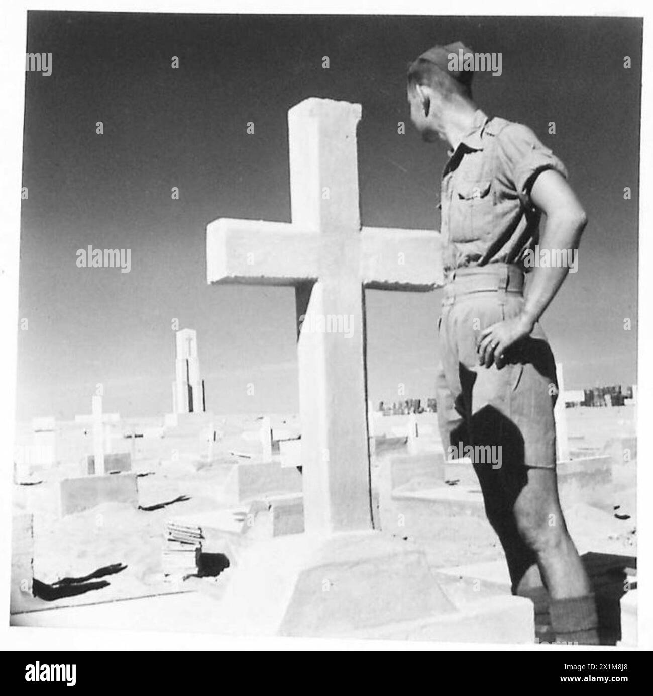 Un soldato britannico ispeziona le tombe nel cimitero adiacente al Memoriale degli Eroi di Tobruk, commemorando i soldati caduti. Foto Stock
