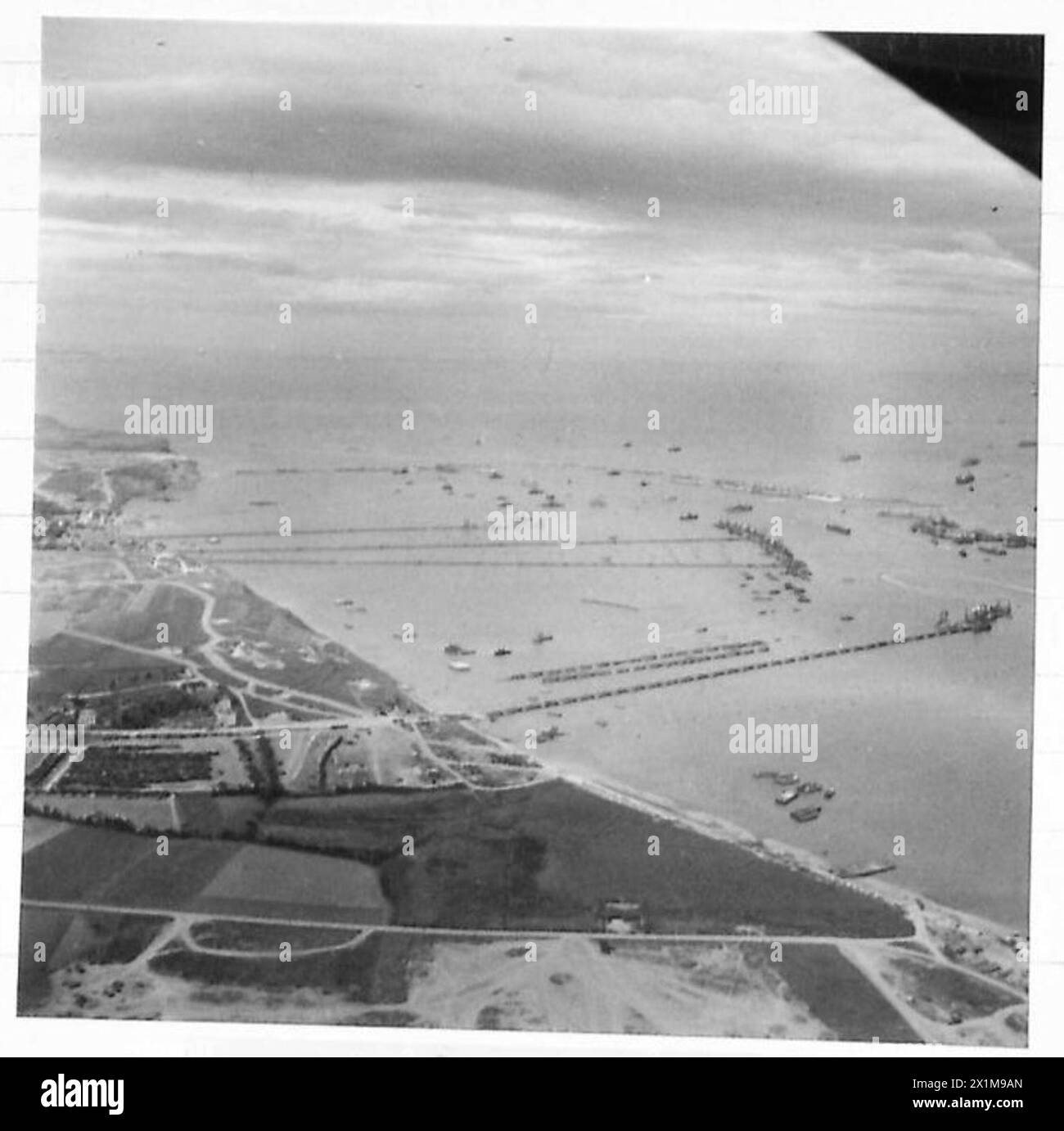 Fotografie aeree catturarono Mulberry B ad Arromanches, mostrando operazioni di ingegneria e logistica dell'esercito britannico nell'Europa nord-occidentale tra il 1944 e il 1946. Foto Stock
