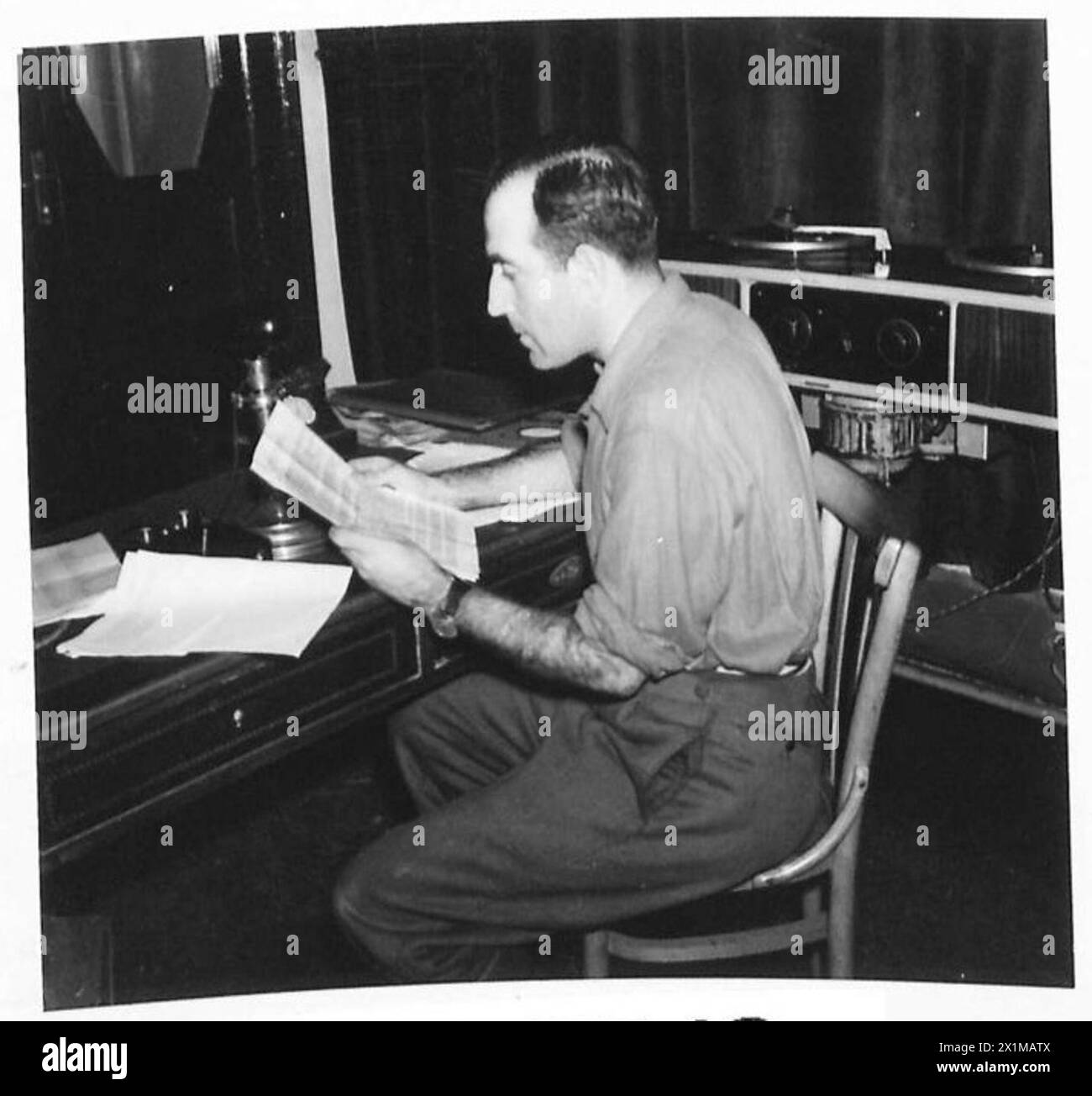 Un soldato dell'Esercito Italiano, Carlo Bressan, legge notizie militari in una stazione radio catturata sotto il controllo dell'VIII Esercito britannico. Foto Stock