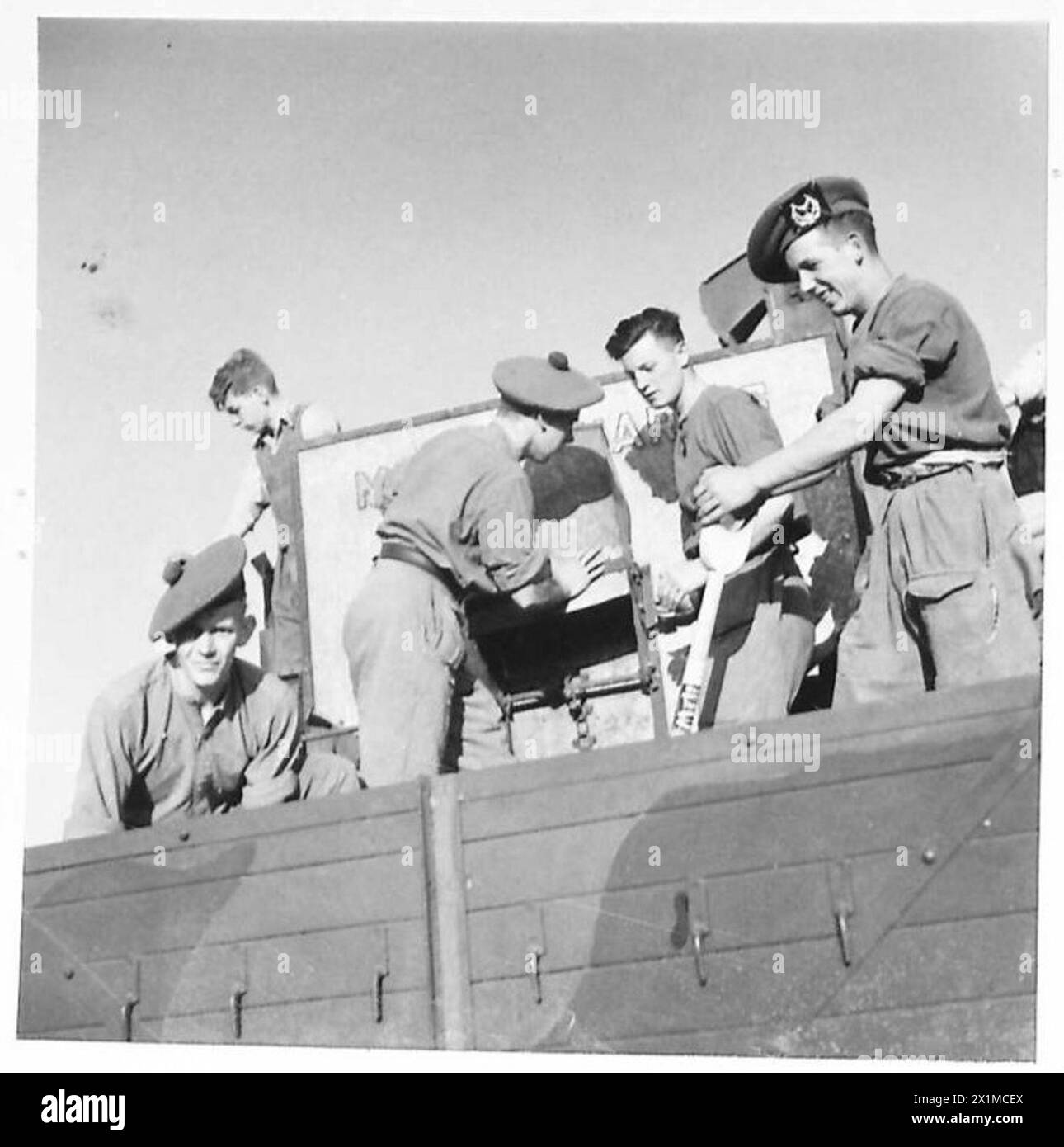 I soldati dell'esercito britannico, assistiti da scolari, svuotarono il grano raccolto nei camion dell'esercito durante le operazioni agricole a sostegno della produzione alimentare in tempo di guerra. Foto Stock