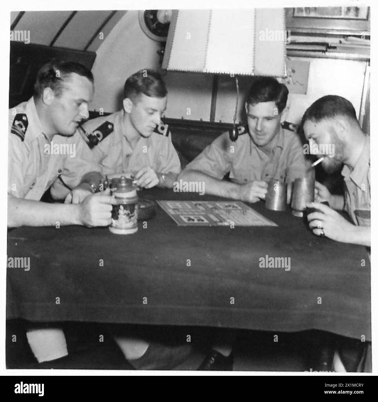 Quattro ufficiali giocano "Ukkers", una versione di Ludo, sul ponte di un sottomarino britannico di notte, mettendo in evidenza le attività di svago e la vita quotidiana a bordo dei sottomarini H.M. Foto Stock Quattro ufficiali giocano "Ukkers", una versione di Ludo, sul ponte di un sottomarino britannico di notte, mettendo in evidenza le attività di svago e la vita quotidiana a bordo dei sottomarini H.M. Foto Stock