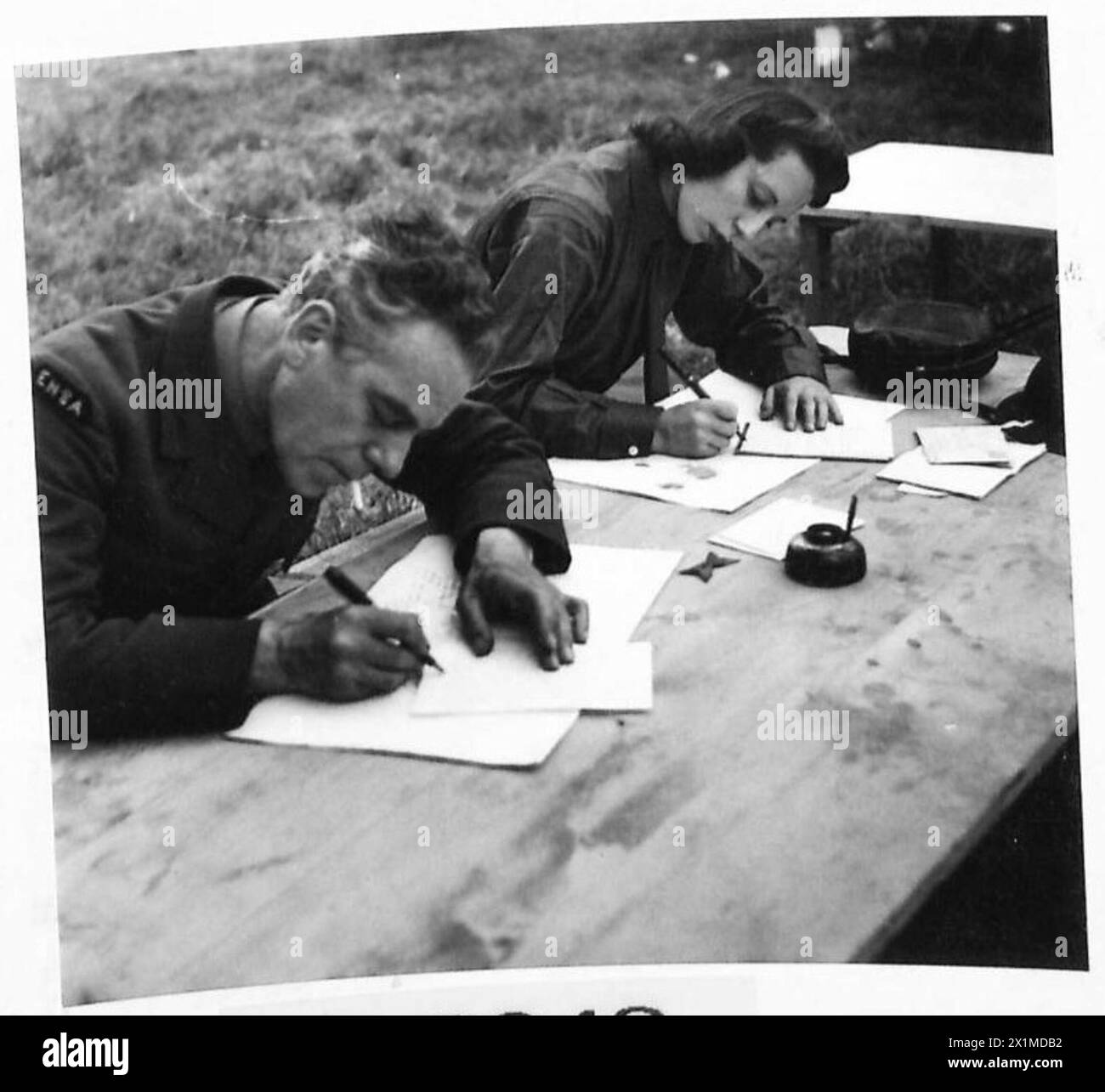Gli intrattenitori June Worth e Lennox Dalton scrivono lettere a casa durante le esibizioni dell'ENSA in Normandia, sostenendo il personale dell'esercito britannico del 21st Army Group. Foto Stock