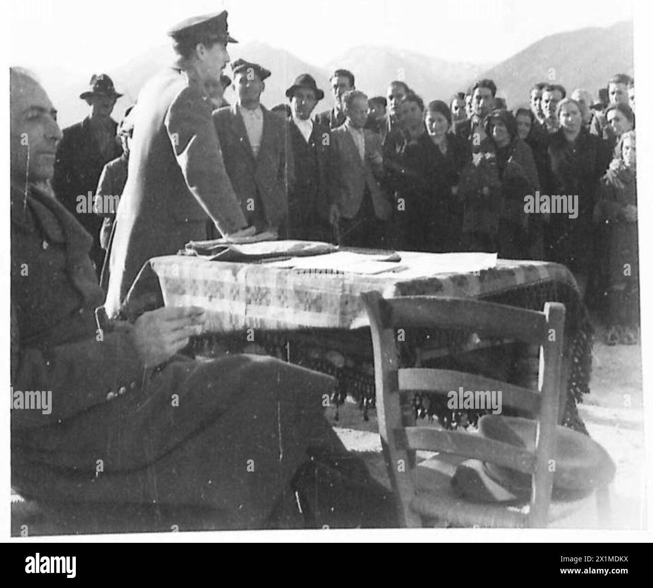 LA COMMISSIONE DI SCREENING ALLEATA RECOMPENSES ITALIANI CHE HANNO AIUTATO A FUGGIRE PRIGIONIERI DI GUERRA ALLEATI - Un maggiore britannico si rivolge agli abitanti di Scoppito vicino Aquila. Questi abitanti sono tipici delle migliaia di italiani che hanno nutrito, vestito e riparato ex POW alleati dopo l'armistizio italiano del 1943. Il maggiore - egli stesso ex prigioniero di guerra - ringrazia pubblicamente gli aiutanti per il loro lavoro, prima di distribuire un compenso monetario, British Army Foto Stock