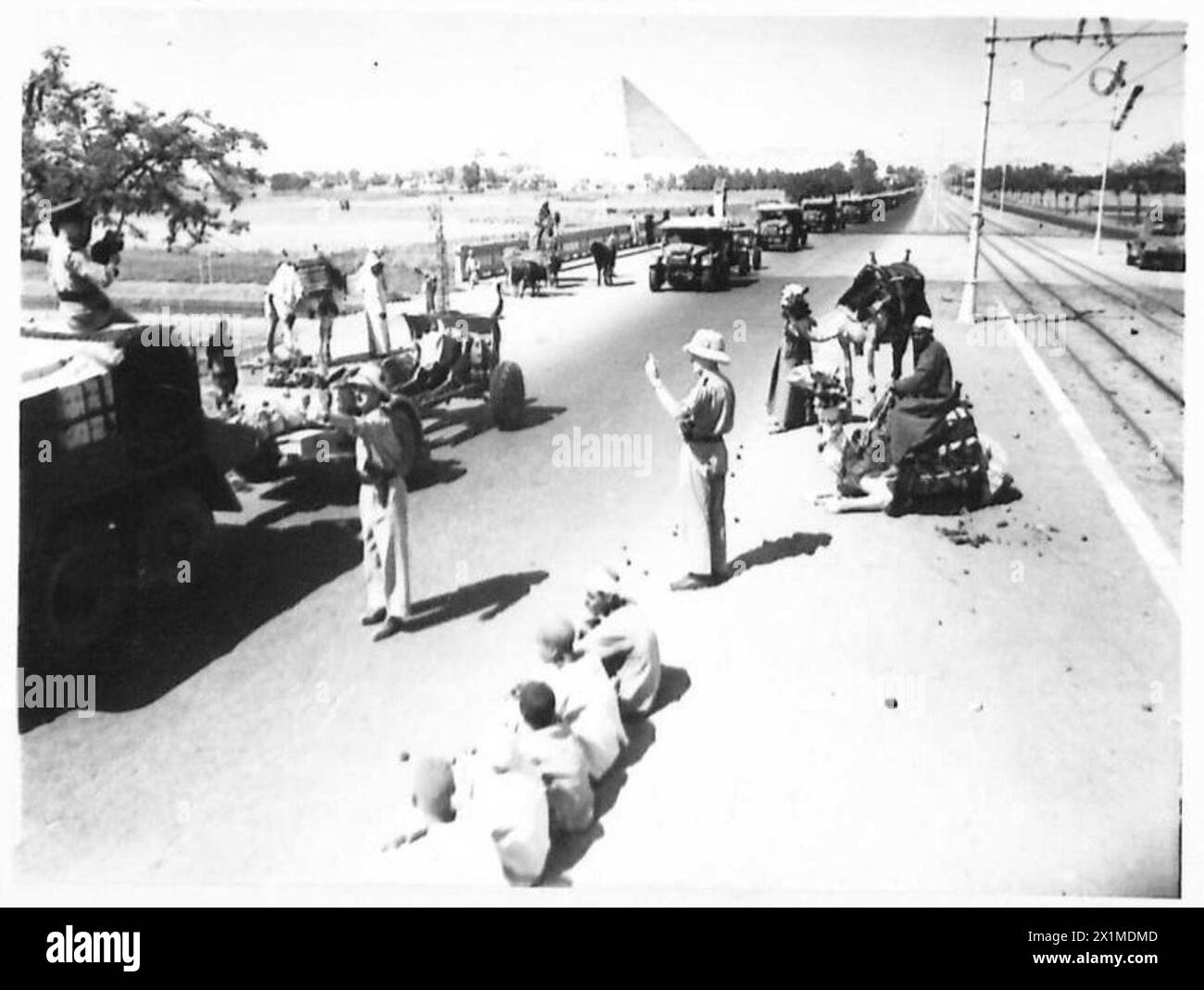 Una colonna di artiglieria da campo dell'esercito britannico si muove attraverso il deserto, osservata dai nativi locali e dai cammelli, illustrando la logistica militare e le operazioni di trasporto in condizioni aride. Foto Stock