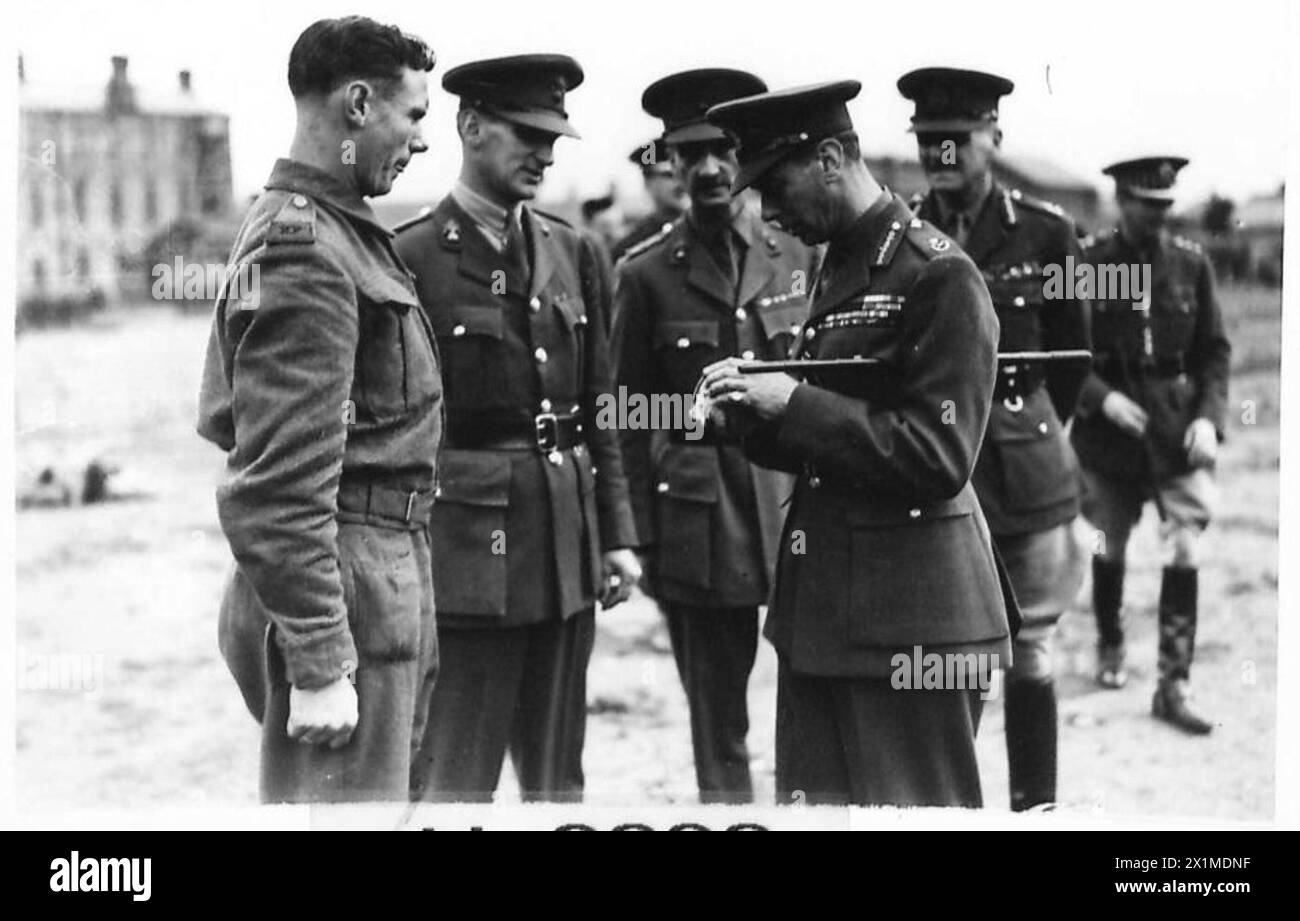 Sua Maestà il Re ispeziona le reclute in addestramento mentre maneggiano una bomba Mills, l'esercito britannico. Foto Stock
