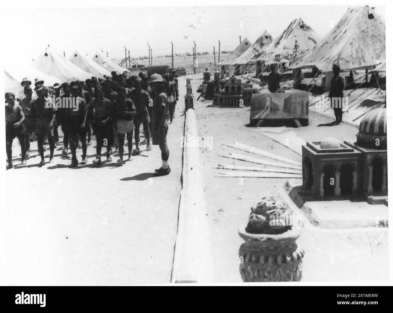 I prigionieri di guerra marciano davanti a una linea di tende che espongono i modelli che hanno fatto nel campo, British Army. Foto Stock