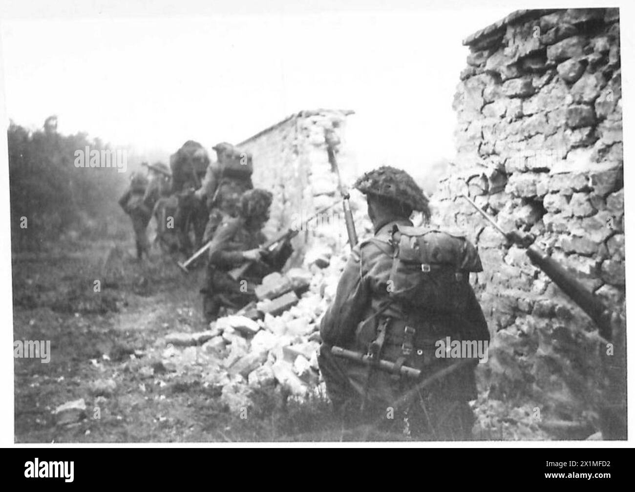 Le truppe britanniche del 6th Royal Scots Fusiliers, 11th Armoured Division, si muovono cautamente intorno a un muro in rovina a St Mauvieu, Normandia, Francia, preparate ad affrontare le forze nemiche durante la campagna alleata nell'Europa nordoccidentale, 1944-1945. Foto Stock