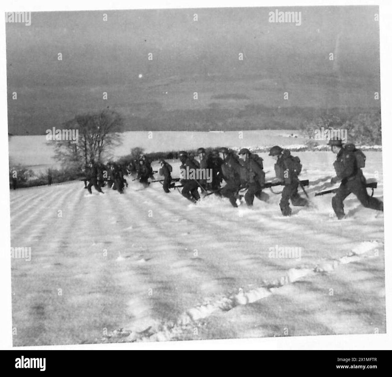 Il personale dell'esercito britannico avanza in formazione attraverso i campi innevati durante un allenamento invernale. Foto Stock