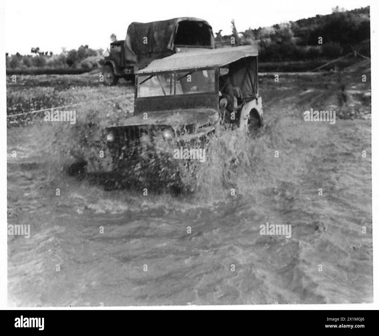 Una jeep dell'Eighth Army attraversa un guado gonfio durante le forti piogge, illustrando le sfide di mobilità a terra in condizioni di guerra. Foto Stock
