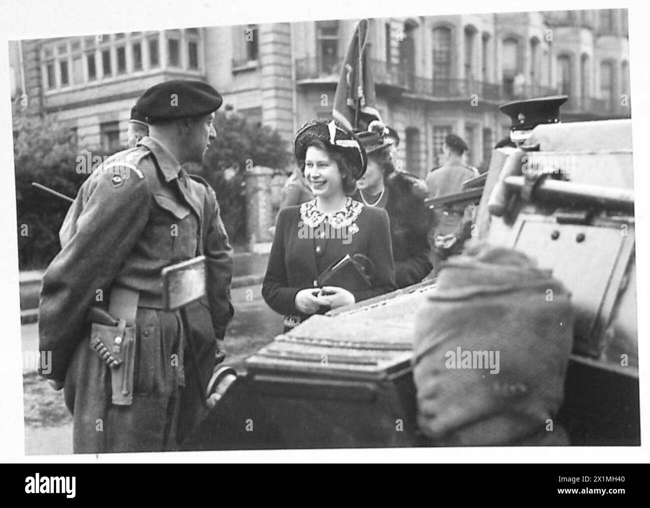 H.R.H. la Principessa Elizabeth viene mostrata in visita alla Divisione corazzata della Guardia, discutendo di un'auto corazzata con un ufficiale. L'immagine cattura un'ispezione reale e l'interazione con il personale militare. Foto Stock