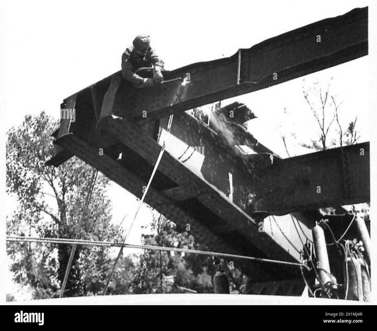 RES SOSTITUISCE IL PONTE FERROVIARIO SUL FIUME ORNE - Un ingegnere reale con il suo tubo di soffiaggio, al lavoro in alto sul fiume Orne tagliando via una delle sezioni della trave "Rocker", British Army, 21st Army Group Foto Stock