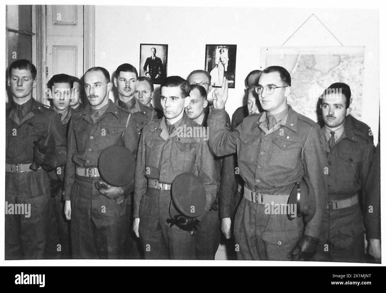 Un cadetto dell'esercito reale olandese presta giuramento durante una cerimonia di messa in servizio, alzando la mano come parte della procedura formale. Foto Stock