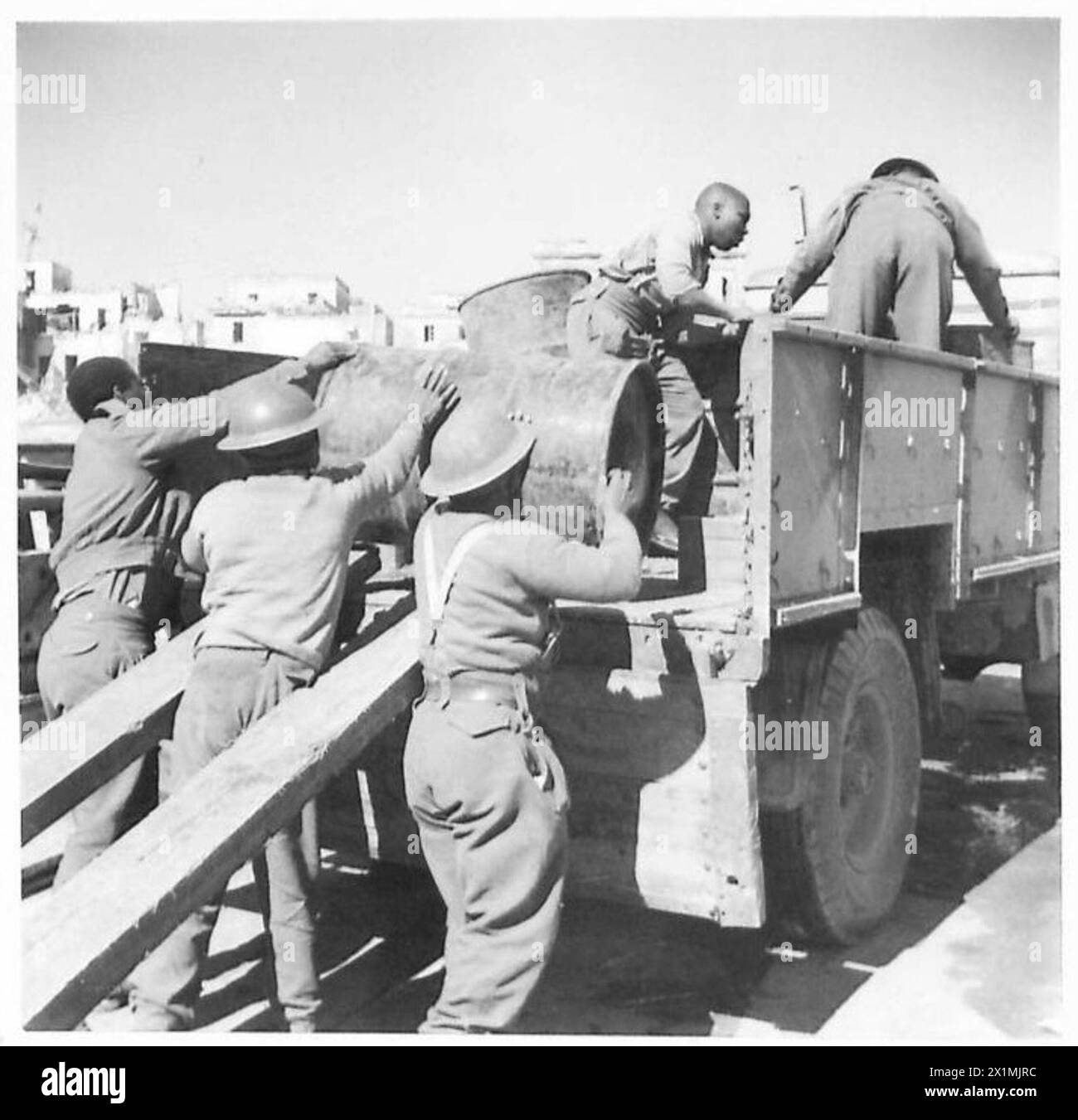 Le truppe Swazi sudafricane caricano tamburi di benzina su un camion posizionato su un mezzo da sbarco alla testa di ponte di Anzio mentre cantano una canzone nativa, Fifth Army, British Army. Foto Stock