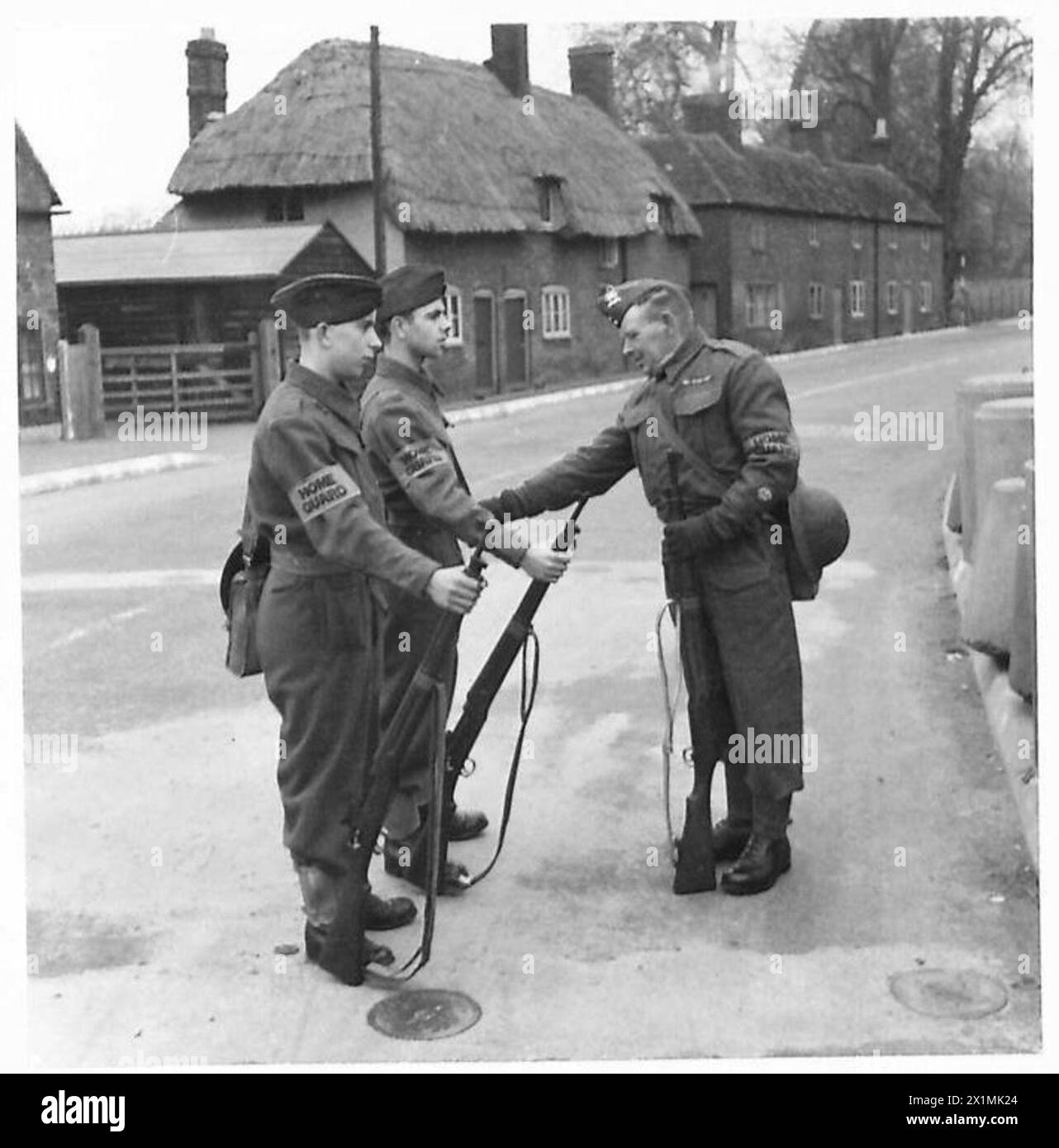Il sergente maggiore V. Hollness, di 53 anni, ispeziona i suoi figli Harold e John, di 17 anni, prima di una parata domenicale della Home Guard, personale dell'esercito britannico presente. Foto Stock