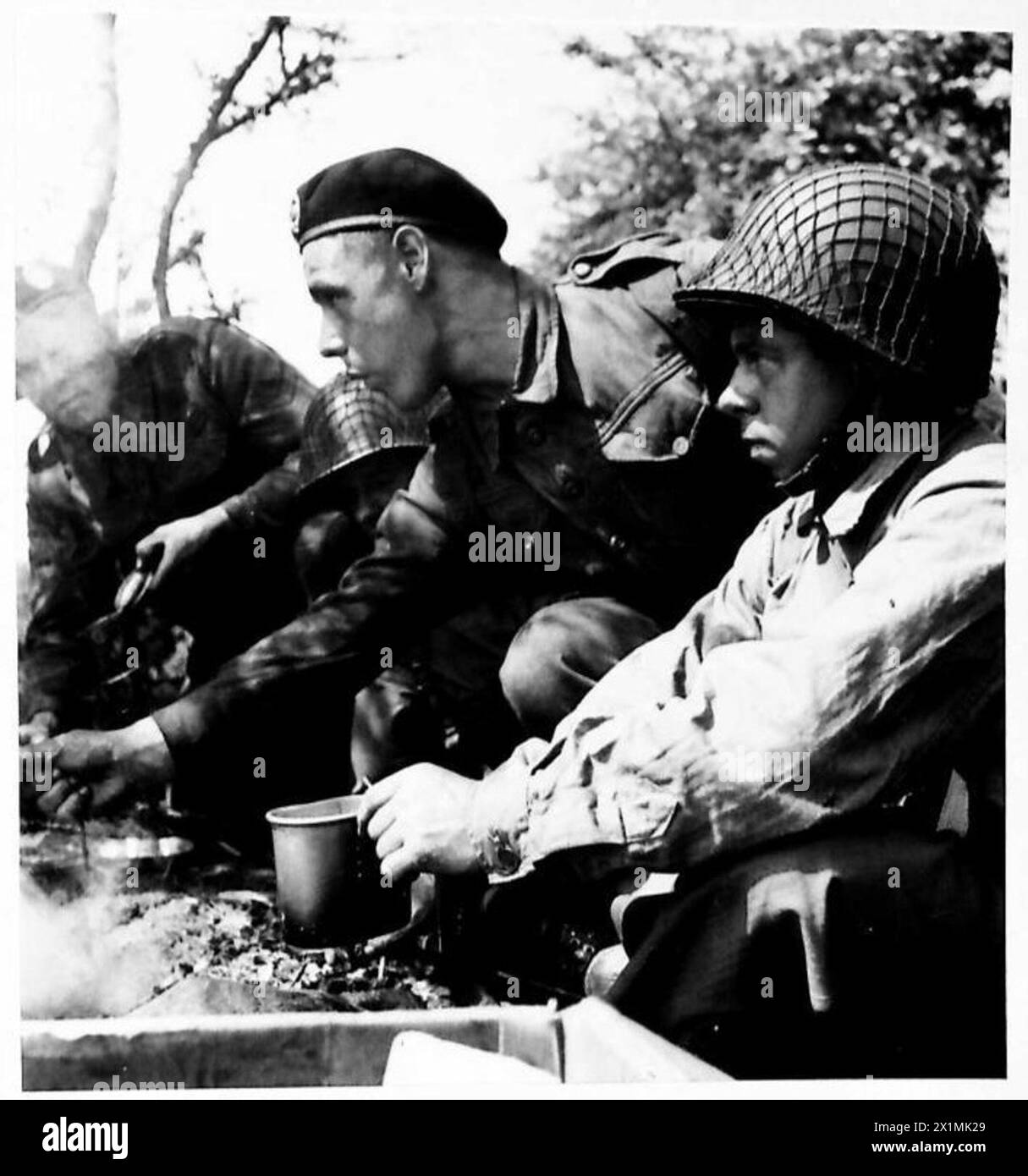 Un'unità di ricognizione britannica (RECCE) collabora con le forze americane durante un'esercitazione sul campo. Il personale condivide un pasto di mezzogiorno su un fuoco da campo comune, illustrando la cooperazione tra le due unità militari. Foto Stock