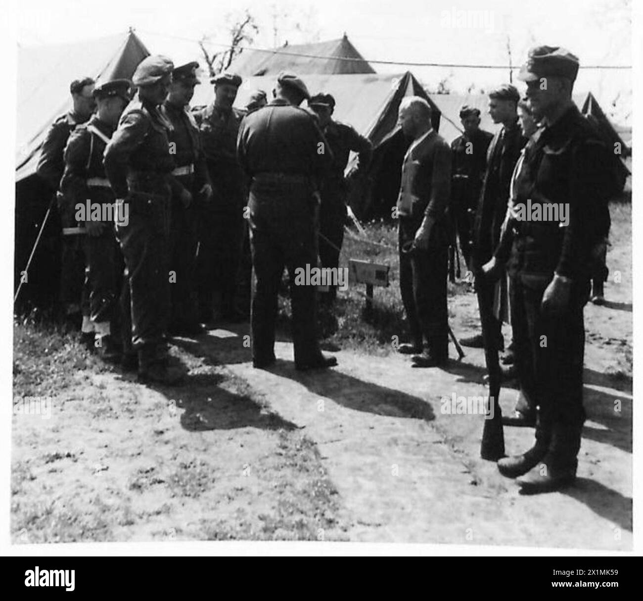 In un campo di sfollati, il personale russo identifica un tedesco che nasconde un'arma e lo consegna alle autorità, sotto la supervisione dell'esercito britannico, 21st Army Group. Foto Stock