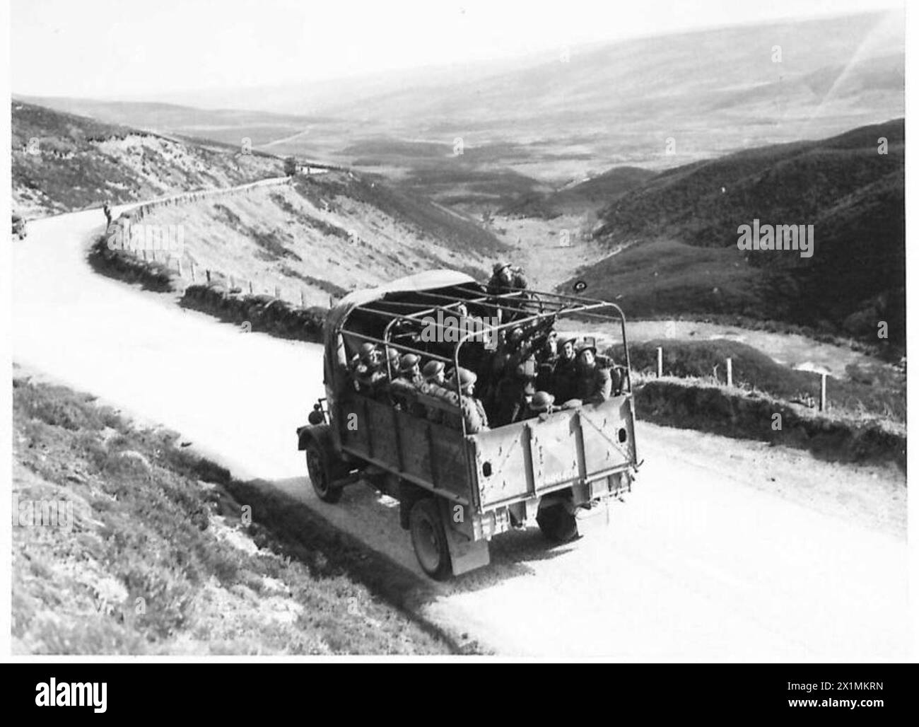 Le truppe avanzano su un camion mentre un cannoniere Bren fornisce difesa aerea durante le operazioni in Scozia, British Army. Foto Stock