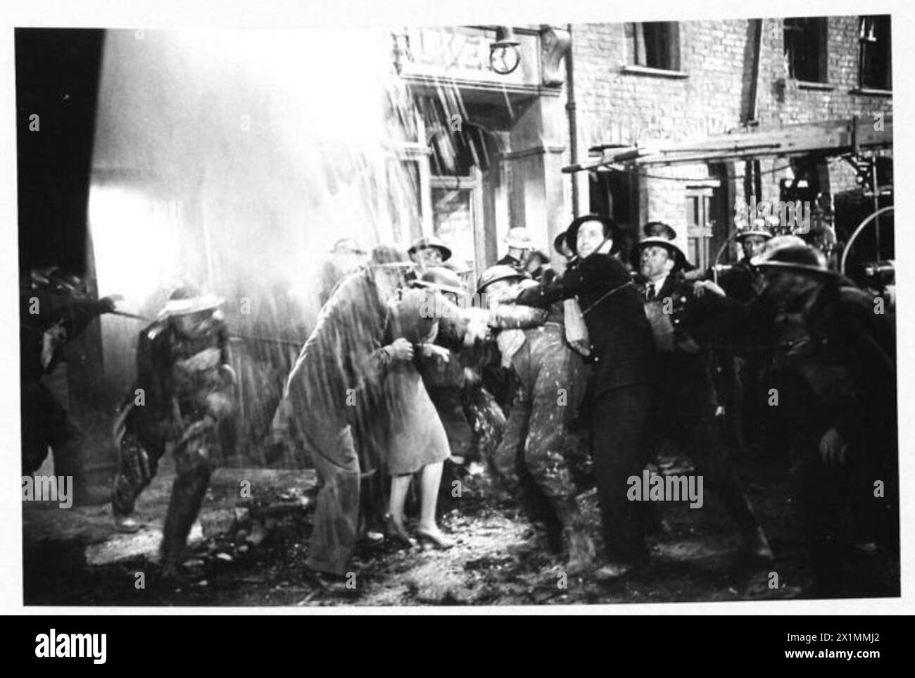 Durante le riprese di "Unpublished Story" ai Denham Studios, attori e personale dei servizi antincendio ausiliari simulano un crollo del muro vicino a una cabina telefonica per rappresentare il Blitz del 1940 sui moli di Londra. Foto Stock