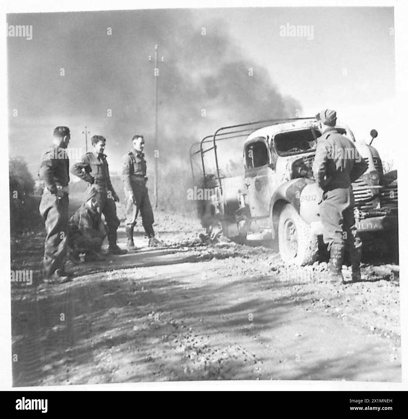 La polizia militare dell'ottava Armata osserva il loro camion bruciare dopo un raid aereo tedesco vicino a Castel Frentano in Italia. Foto Stock