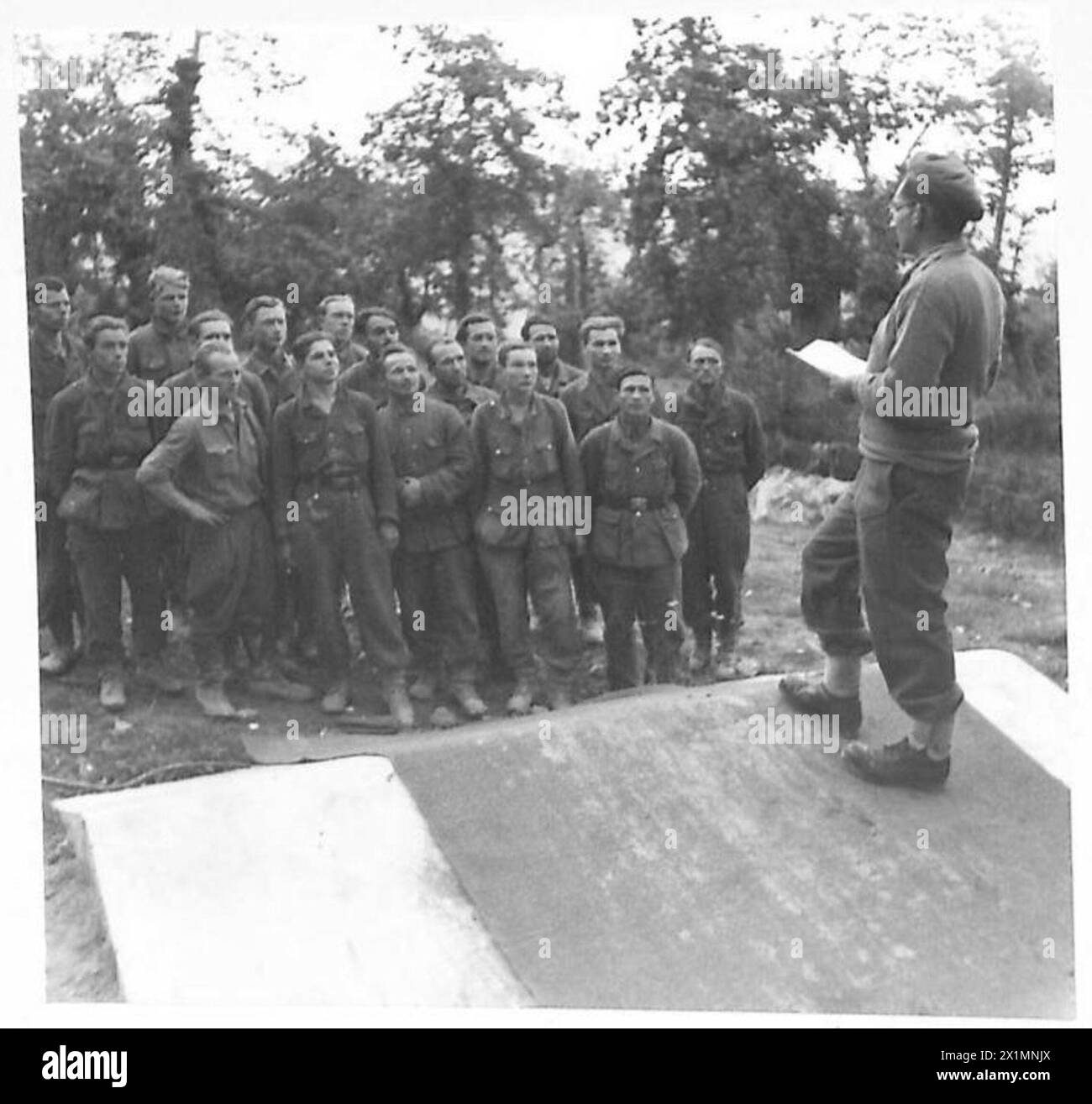 QUINTO ESERCITO : VARIO - Un certo numero di russi fuggì dai tedeschi sulle colline e si unì ai partigiani italiani. Questo gruppo di 17 civili e 9 soldati russi ha finalmente lavorato per le nostre linee. La foto mostra l'interprete della 24 guardie che spiega che saranno mandati alle nostre spalle per un eventuale rimpatrio. I civili rivelarono che erano stati portati nei campi di P0W tedeschi dove il cibo era deliberatamente al di sotto del livello di sussistenza, al fine di costringerli a fare volontariato per lavorare nei battaglioni di lavoro, l'esercito britannico Foto Stock