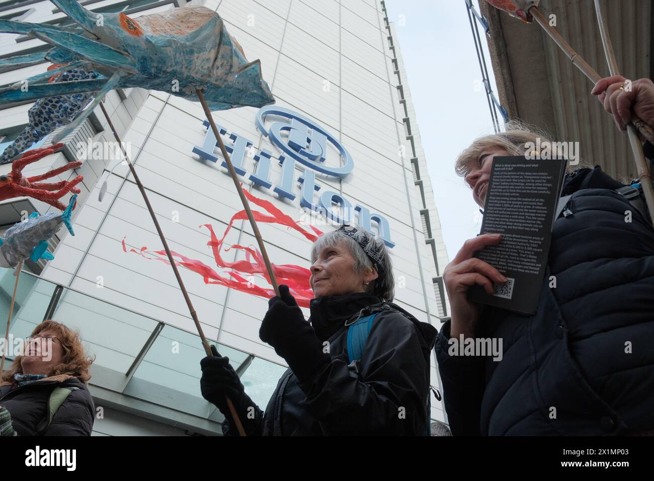 Londra, Inghilterra, Regno Unito. 17 aprile 2024. Ocean Rebellion (OR) organizza un concerto di protesta contro una cima mineraria in alto mare all'Hilton di Canary Wharf, evidenziando i suoi effetti dannosi sulla vita marina. Si ritiene che l'estrazione di˜noduli di manganese dai fondali marini per l'uso nelle tecnologie verdi provochi notevoli danni ambientali. Si schiaccia il fondale marino della vita, rilascia pennacchi di sedimenti e crea rumore che disorienta gli animali marini. L'inquinamento acustico causato dalle miniere d'altura è centinaia di volte più forte di un lancio di razzi spaziali. Un pidocchio da miniera d'altura Foto Stock