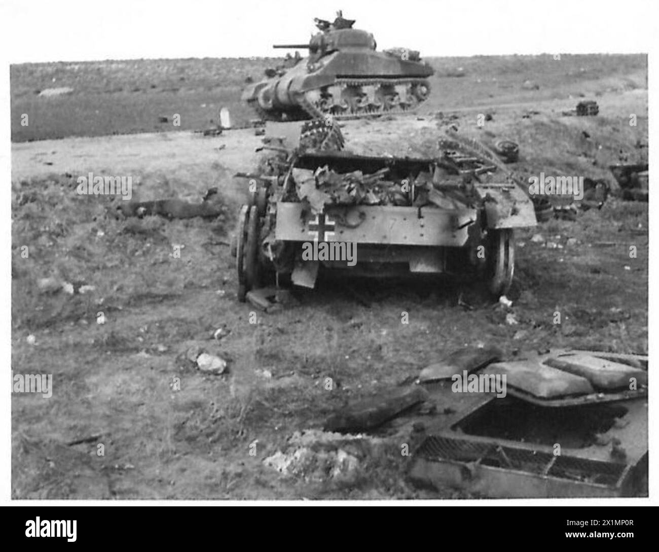Un equipaggio britannico maneggia un carro Sherman americano che passa davanti a un carro armato tedesco distrutto durante la battaglia sul fronte Kasserine, British Army. Foto Stock