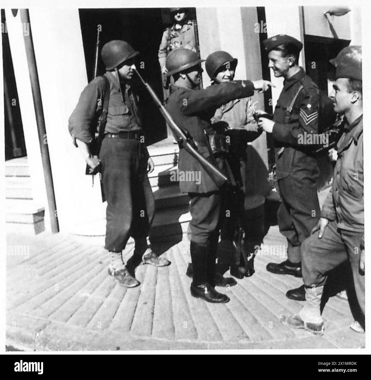 Durante l'operazione Torch nel novembre 1942, un soldato francese interagisce con le truppe britanniche della 78th Division e della 34th Division fuori da un hotel ad Algeri dove il personale italiano è sotto sorveglianza. Foto Stock