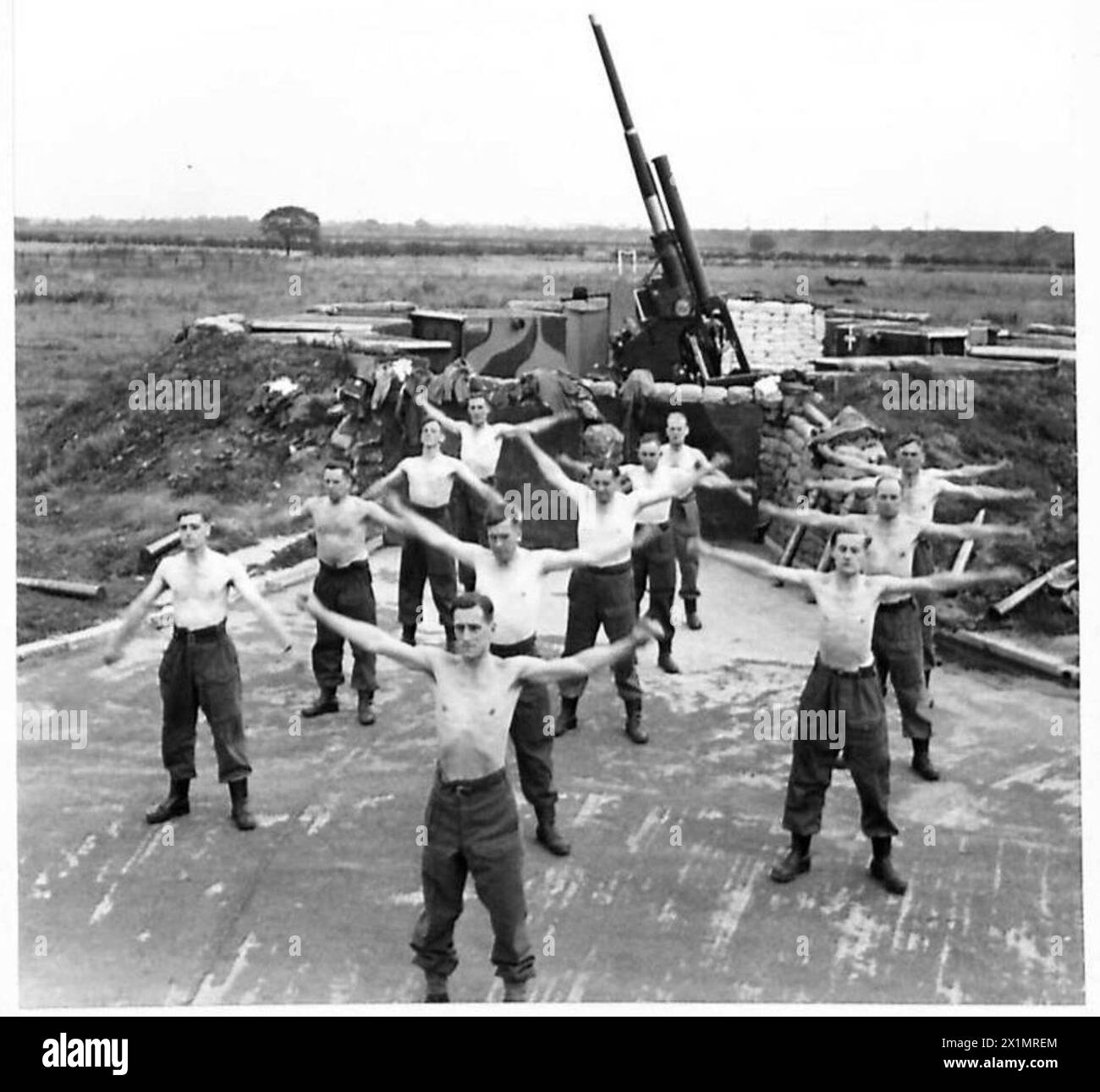 Il C.S.M. Instructor G.H. Swindin guida gli equipaggi delle armi dell'esercito britannico in esercizi di addestramento fisico davanti ai loro cannoni. Foto Stock