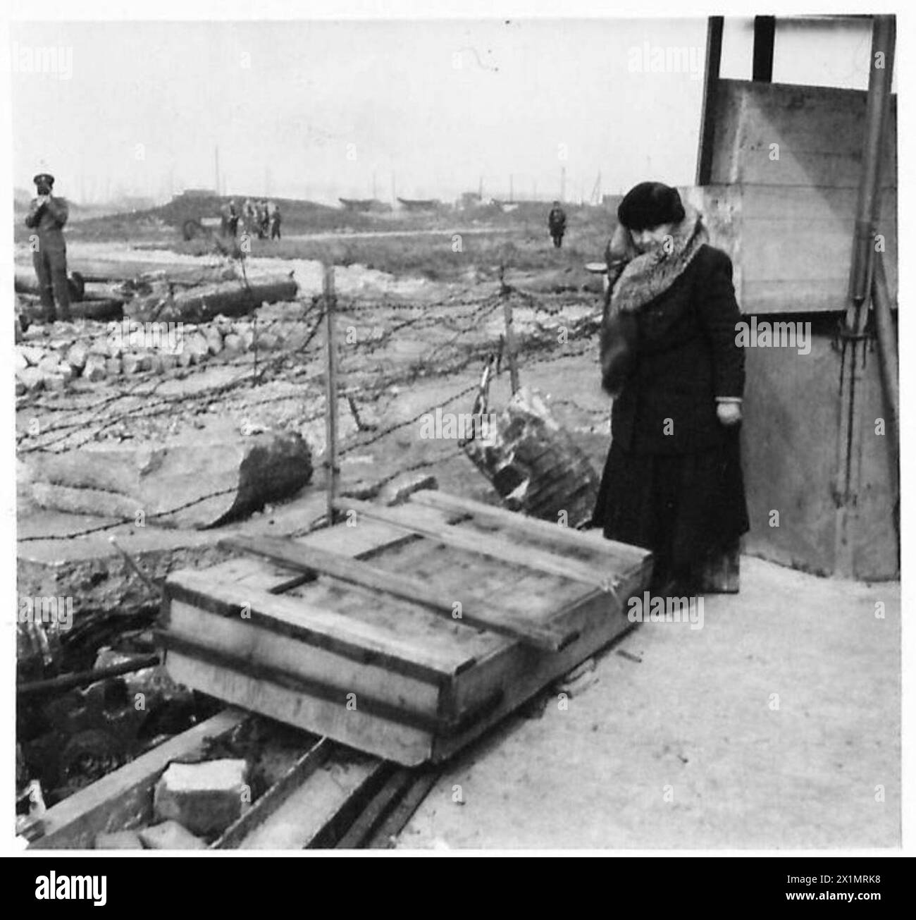 La regina visita un sito della banca del canale dove sono stati giustiziati i custodi delle chiuse, posizionando una rosetta su una pietra commemorativa; una sopravvissuta cammina accanto a lei, British Army, 21st Army Group. Foto Stock