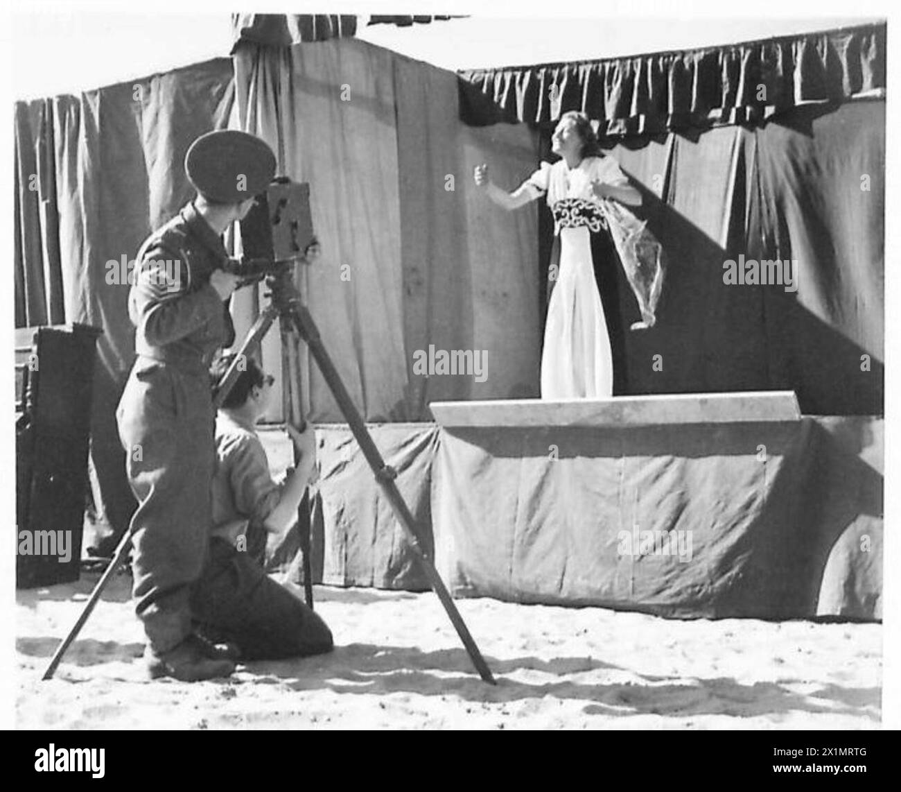 Un cameraman dell'Army Film Unit filma Doris Palmer, protagonista di un concerto della E.N.S.A. in tour in Medio Oriente, il personale dell'esercito britannico è presente. Foto Stock