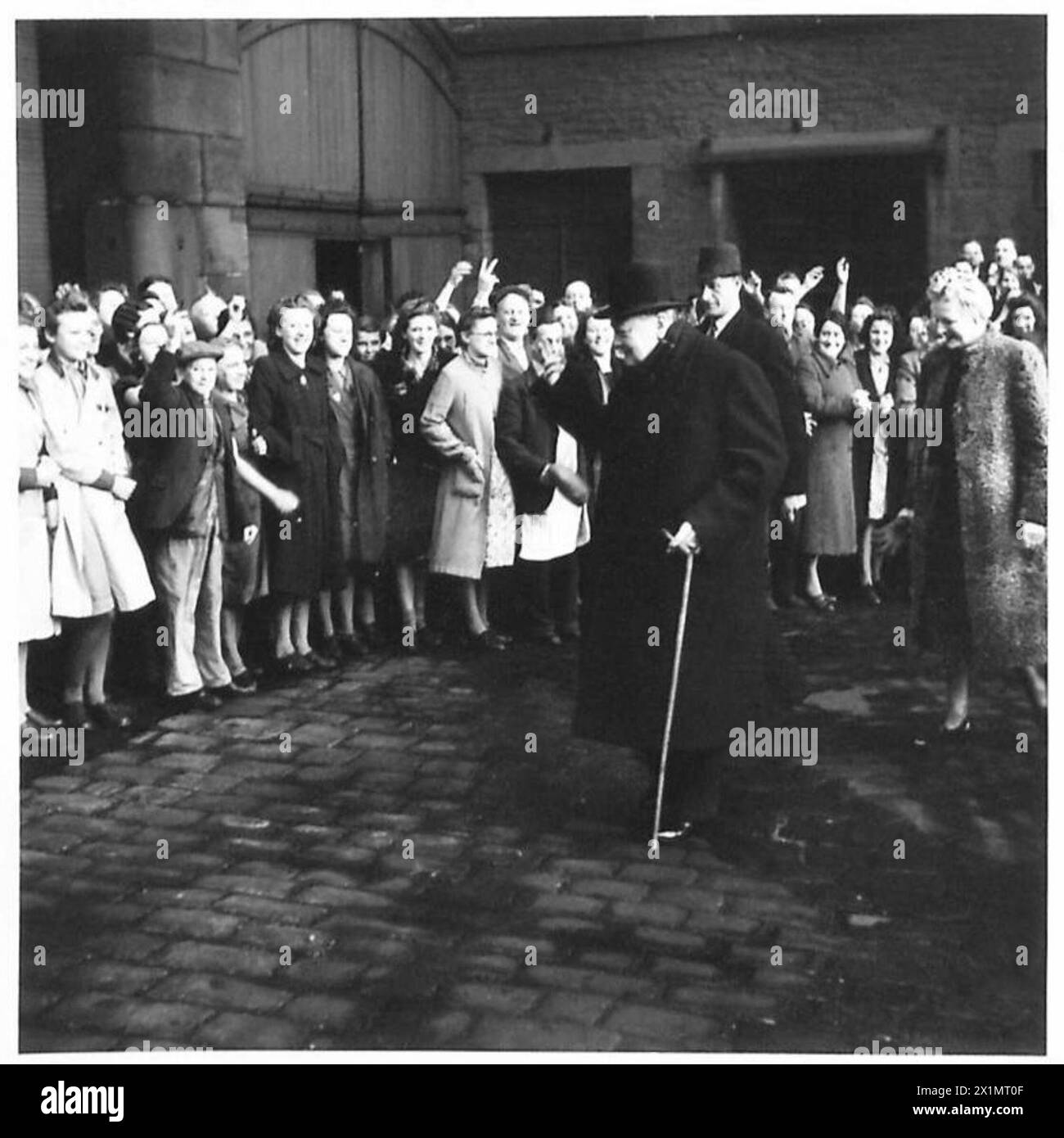 Il primo ministro Winston Churchill e la signora Churchill camminano intorno a un mulino a Bradford durante una visita, osservando l'industria locale e i lavoratori. Foto Stock