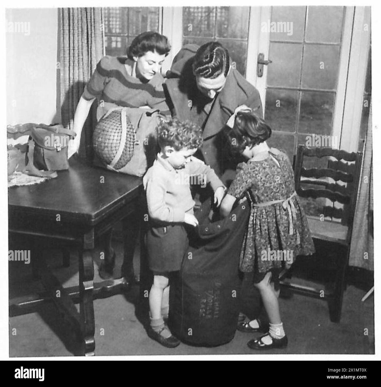 Un soldato dell'Ottava Armata in congedo condivide con i bambini gli oggetti del suo zaino, evidenziando la connessione tra casa e fronte durante la guerra. Foto Stock