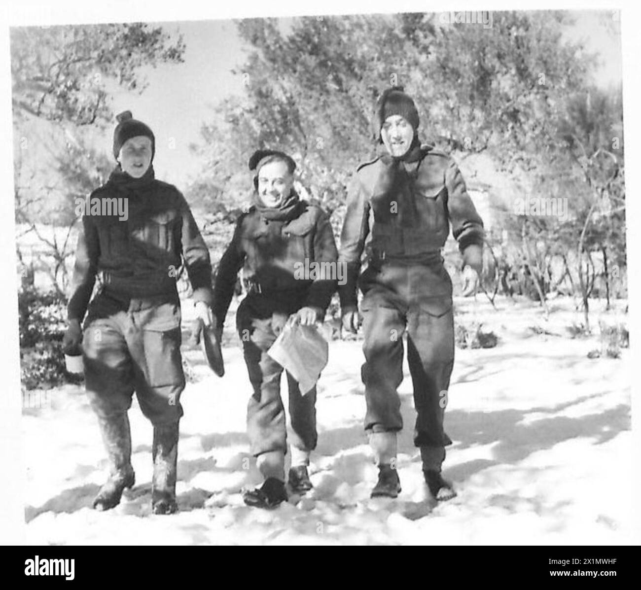 Il generale dell'ottava Armata Friburgo visita una brigata in Italia, osservando tre soldati che camminano attraverso la neve indossando abiti e attrezzature militari appena emessi, British Army. Foto Stock