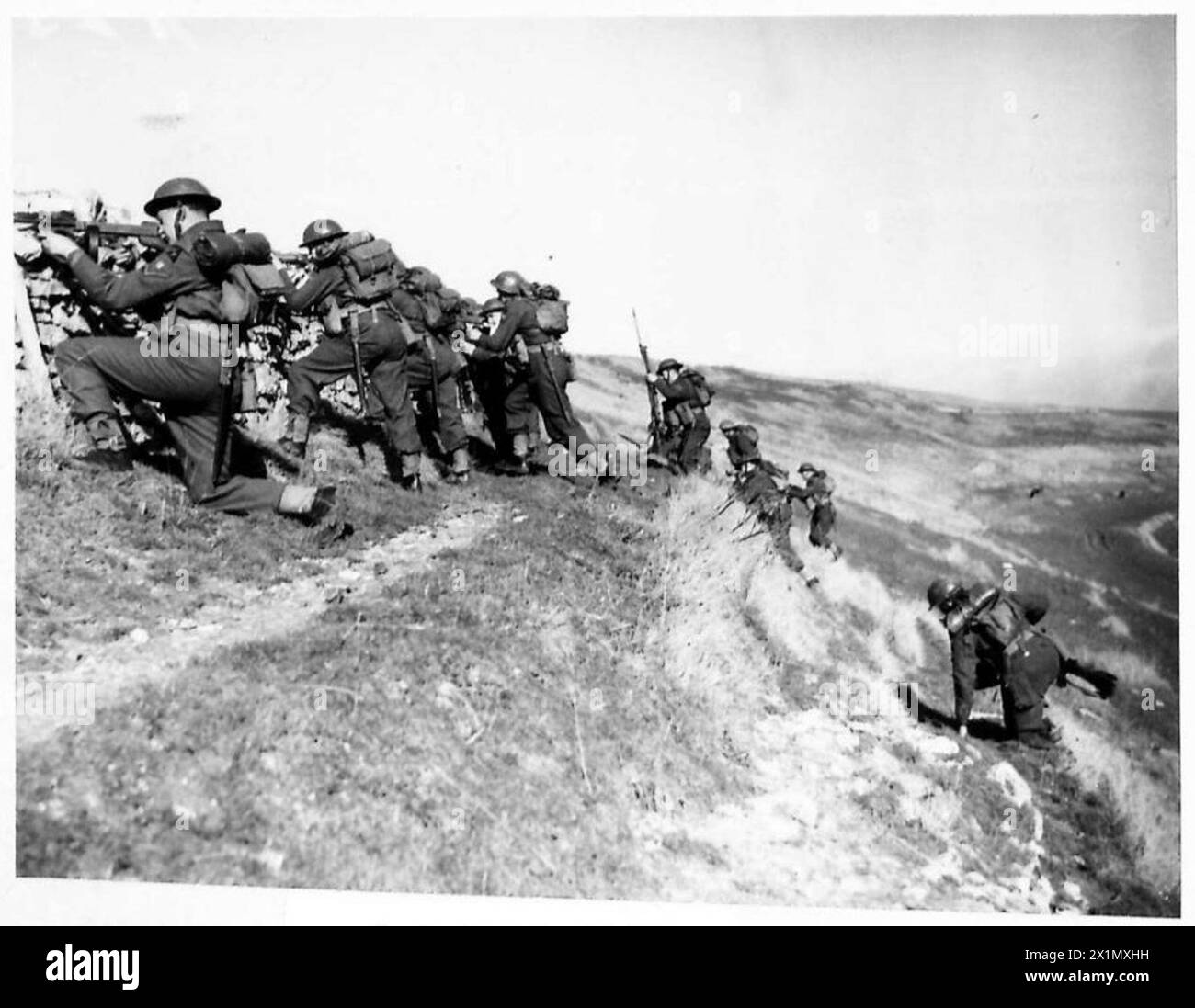 I soldati del Suffolk usano un muro di pietra come copertura durante un'esercitazione d'attacco con l'esercito britannico. Foto Stock