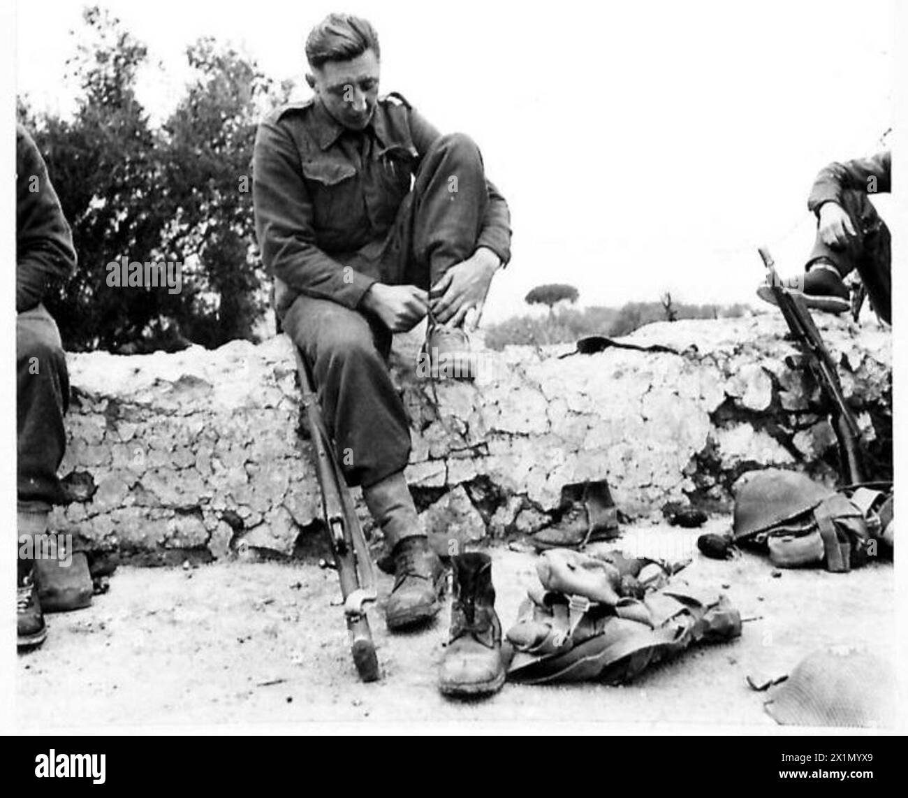 Fux F. Raine del castello di Barnard, contea di Durham, si prepara per una pattuglia di battaglia allacciando gli stivali con l'esercito britannico, la Fifth Army in Italia. Foto Stock