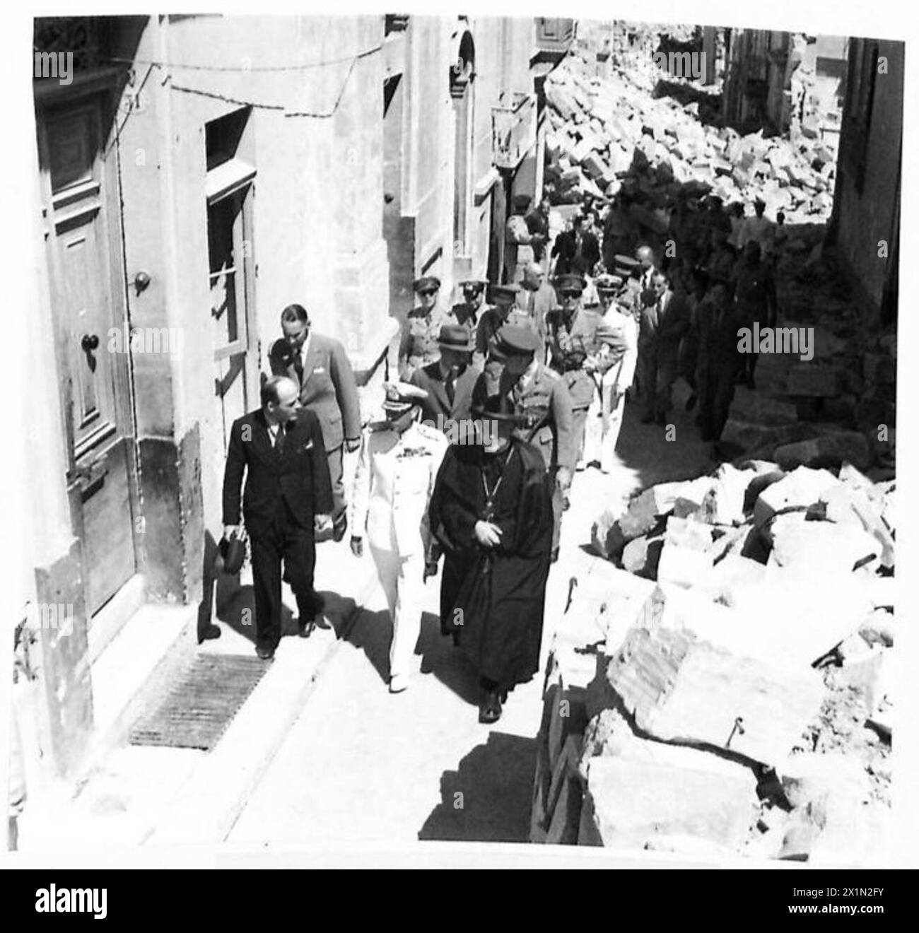 Sua Maestà il Re, accompagnato dal sacerdote parrocchiale, visita le aree bombardate sull'isola di G.C., British Army. Foto Stock