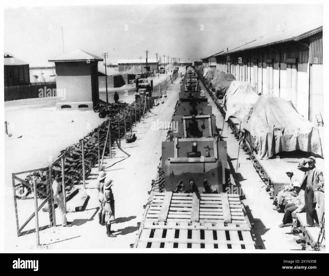 Un treno che trasporta carri armati e un treno separato con cannoni arriva alla banchina in Egitto per l'esercito britannico. Foto Stock