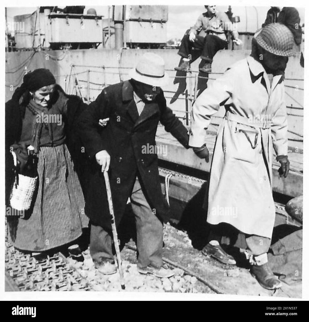 Una coppia anziana viene assistita su un mezzo da sbarco L.C.I. da un funzionario A.M.G. durante l'evacuazione dei rifugiati dall'area di Anzio da parte della Quinta Armata britannica. Foto Stock