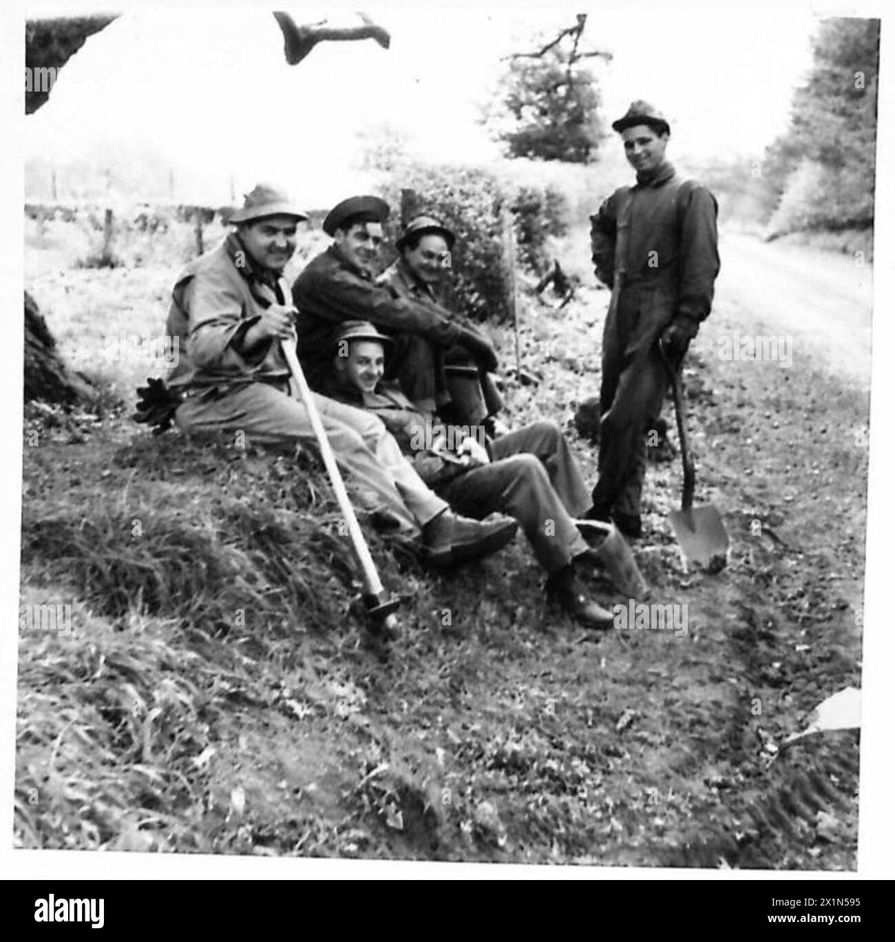 I soldati americani, riutilizzati per compiti agricoli durante la seconda guerra mondiale, sono visti riposare in attesa di ulteriori istruzioni. Ciò riflette l'adattamento del personale militare per sostenere gli sforzi essenziali di produzione alimentare sul fronte interno, evidenziando i ruoli multiforme svolti dai soldati durante la guerra. Foto Stock