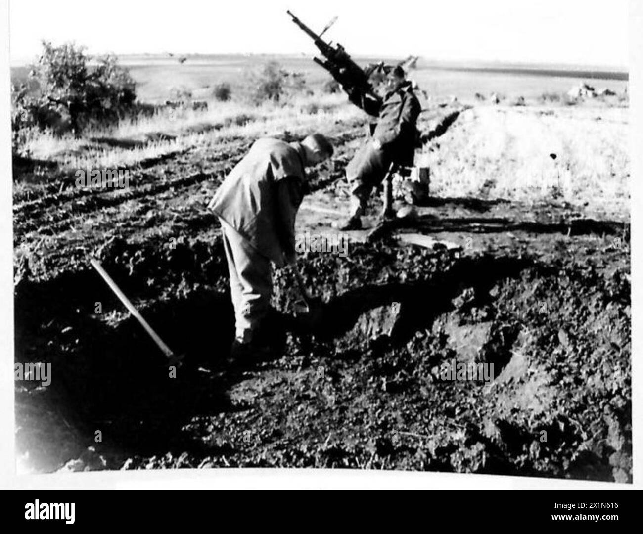 Il LAC A. Johnston del RAF Regiment scava una fossa per cannoni Browning doppi mentre il LAC Orr osserva durante le operazioni di difesa aerea in un terreno di atterraggio in Italia. Foto Stock