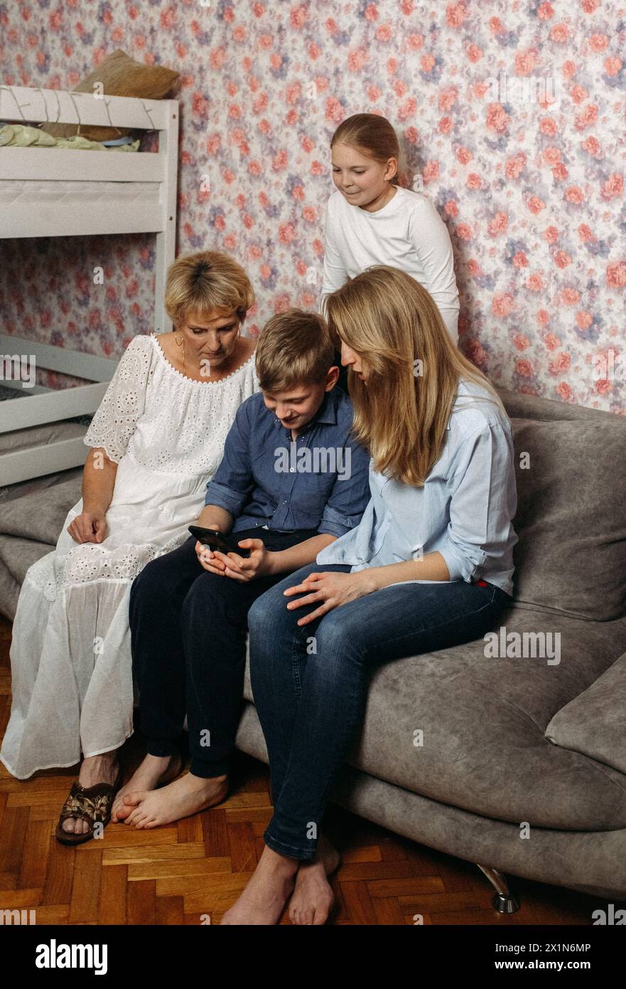Diverse persone sedute insieme su un divano, interagendo e conversando in un salotto. Foto Stock
