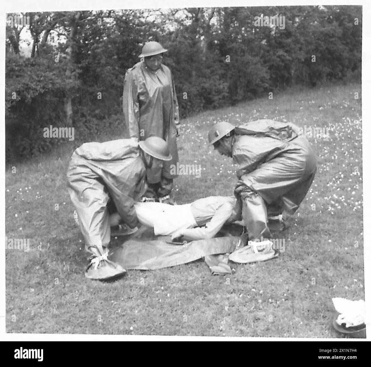 In un Regimental Aid Post, il personale medico avvolge un paziente di blister gassoso in un mantello di gas protettivo dopo la decontaminazione, illustrando le procedure per le vittime chimiche dell'esercito. Foto Stock In un Regimental Aid Post, il personale medico avvolge un paziente di blister gassoso in un mantello di gas protettivo dopo la decontaminazione, illustrando le procedure per le vittime chimiche dell'esercito. Foto Stock